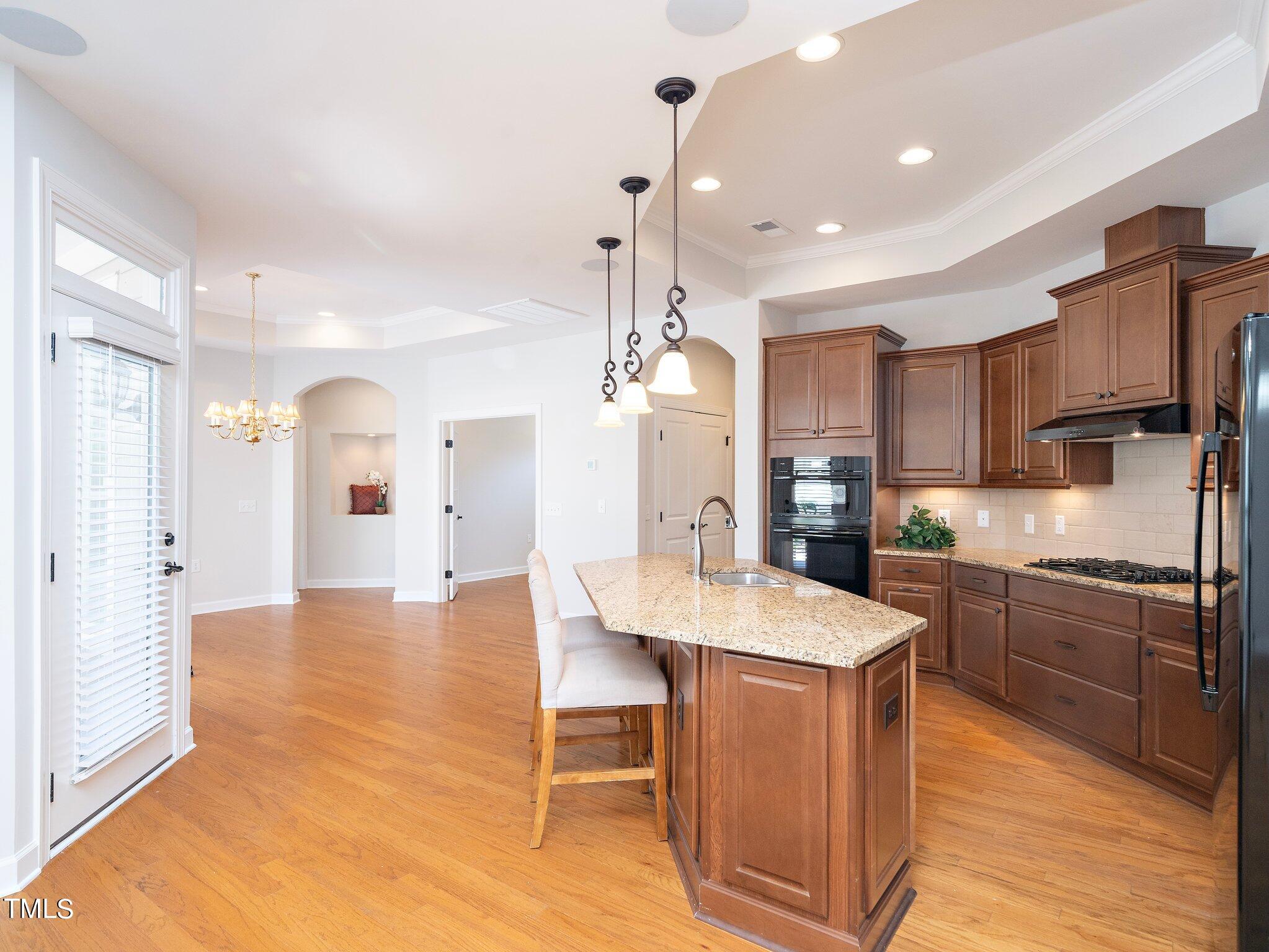 1356 Prevenient Drive Wake Forest, NC 27587 - Photo 10 of 27 a large kitchen with granite countertop a stove a sink a refrigerator and a dining table with wooden floor
