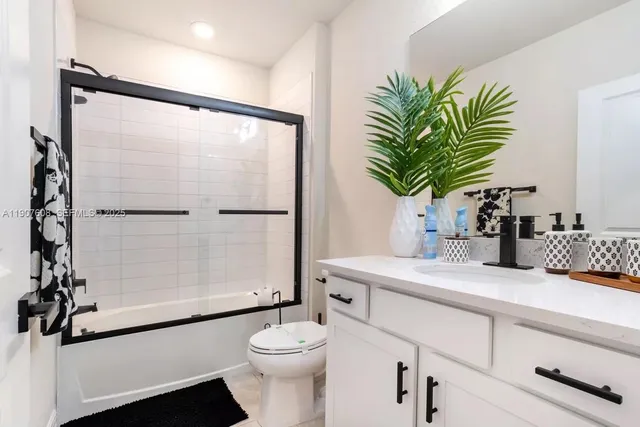 a bathroom with a sink a toilet a glass door a shower and a mirror