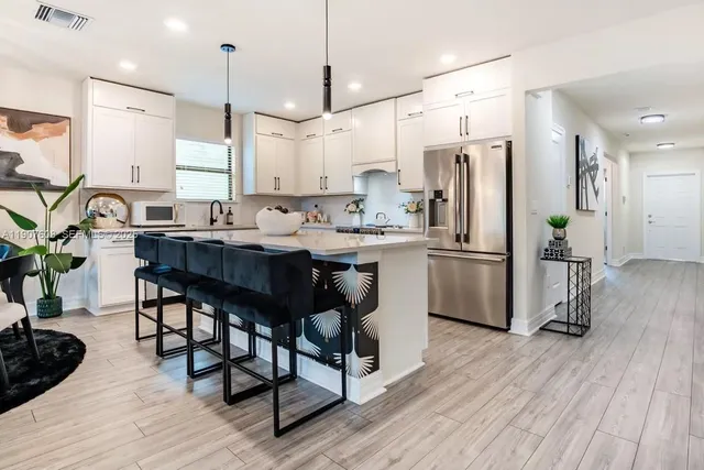 a kitchen with stainless steel appliances a dining table chairs refrigerator and stove