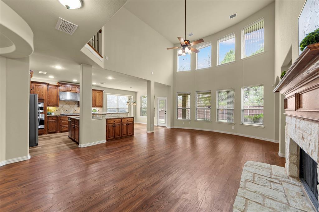 5143 Stream Crest Way Fairview, TX 75069 - Photo 9 of 35 Unfurnished living room featuring a stone fireplace, ceiling fan, dark wood-type flooring, a high ceiling, and recessed lighting