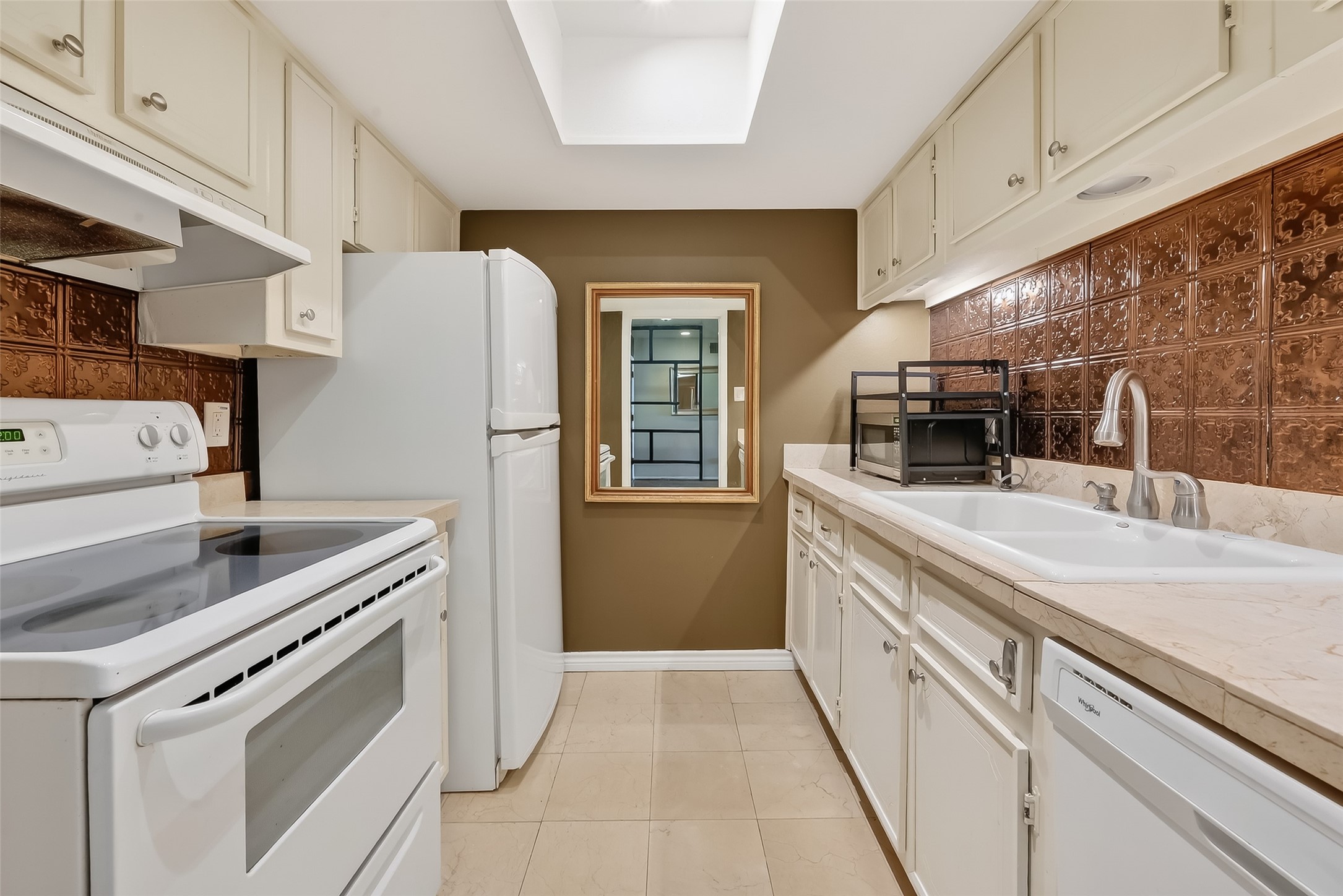 2516 Commonwealth Street, Unit 203 Houston, TX 77006 - Photo 7 of 16 Bright, efficient galley kitchen with ample cabinetry and generous counter space. Light finishes and a skylight bring in natural light, while the window at the end frames a pleasant view and adds warmth to the space.