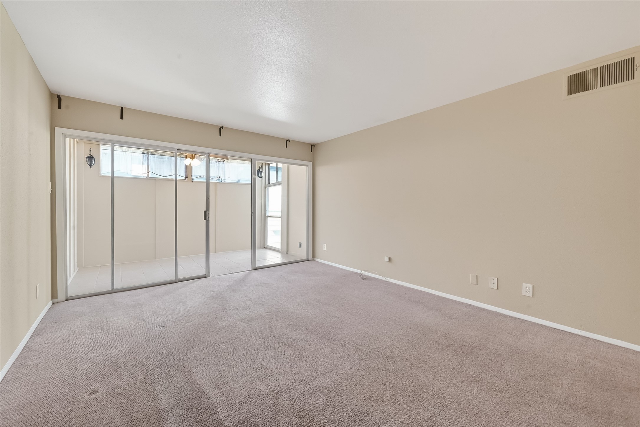 2516 Commonwealth Street, Unit 203 Houston, TX 77006 - Photo 9 of 16 Spacious living room filled with natural light from a wall of sliding glass doors. Neutral tones and clean lines create a bright, open feel, while direct access to the private patio extends the living space outdoors.