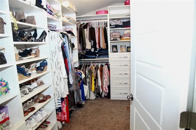 a view of walk in closet with clothes and shoes