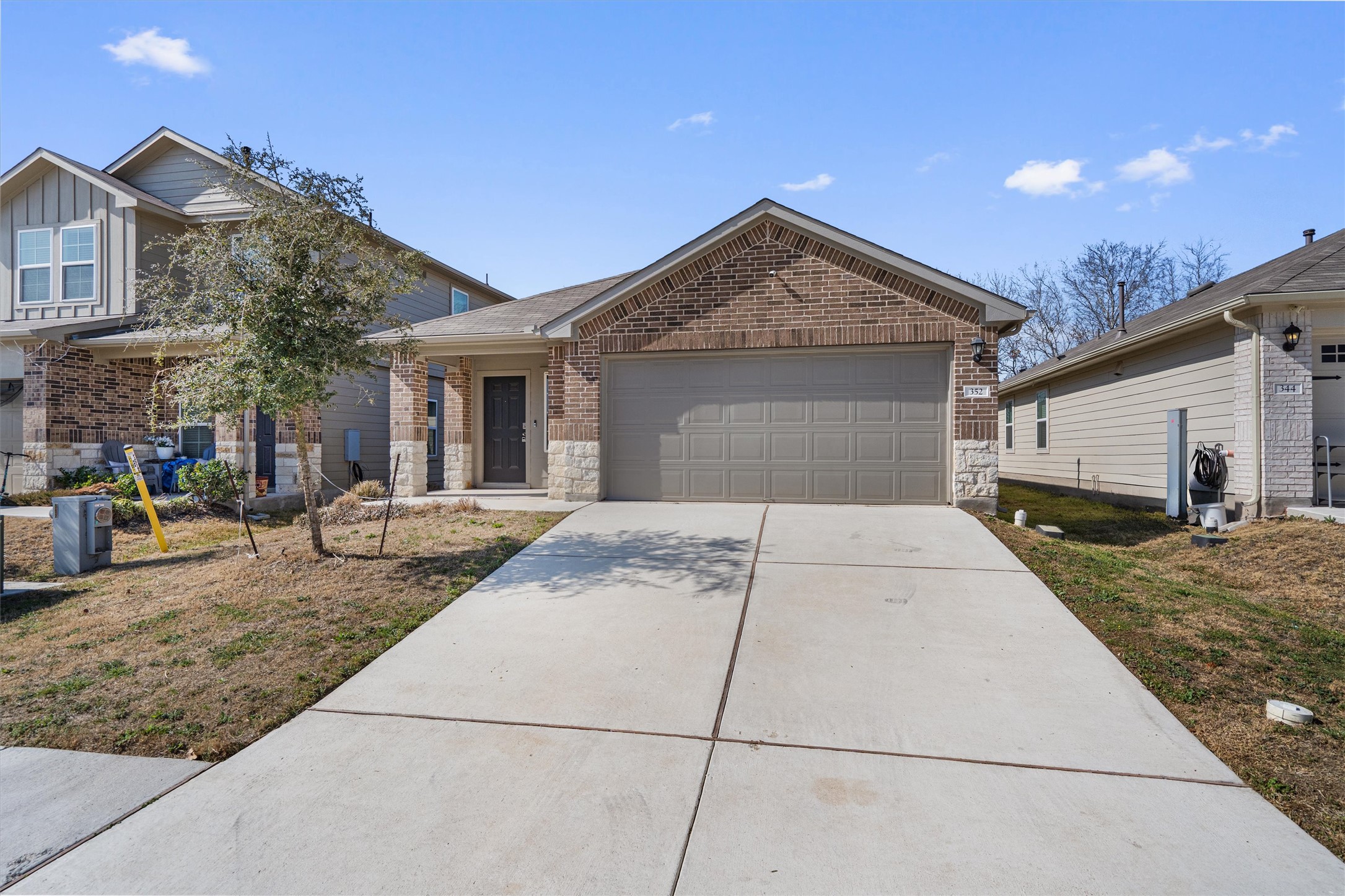352 Sickle Loop Uhland, TX 78640 - Photo 4 of 36 Front exterior showing covered porch, brick façade, and concrete driveway.
