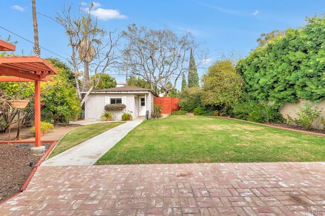 a view of a white house with a yard and potted plants
