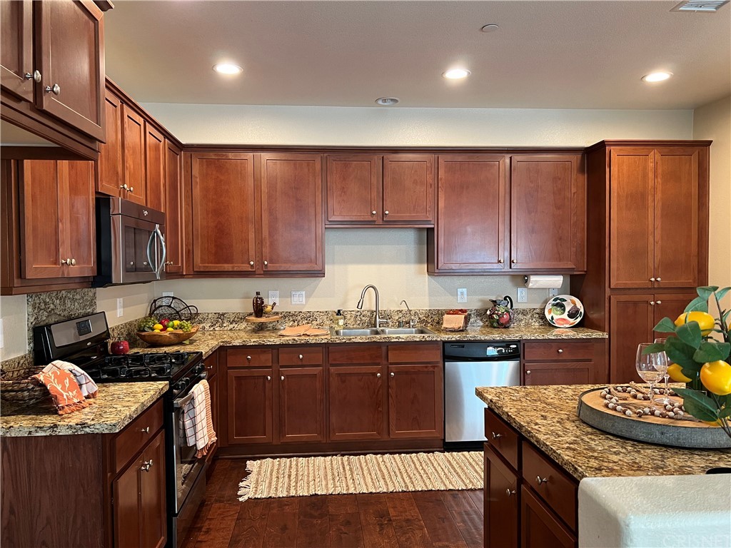 a kitchen with granite countertop stainless steel appliances stove a sink dishwasher and cabinets with wooden floor