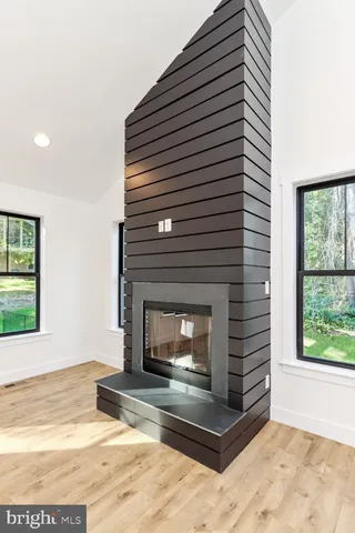 a view of an empty room with wooden floor and a fireplace