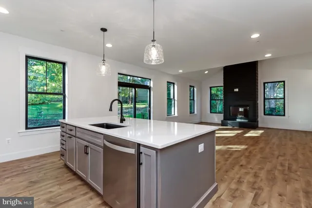 a kitchen with stainless steel appliances granite countertop a sink a stove and a wooden floors