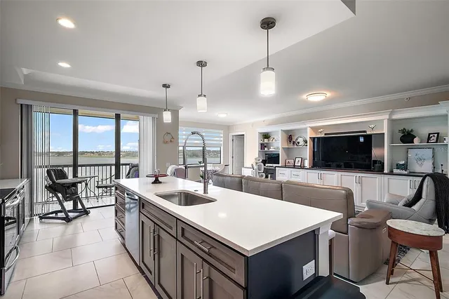 a kitchen with refrigerator a center island a stove and a dining table with wooden floor