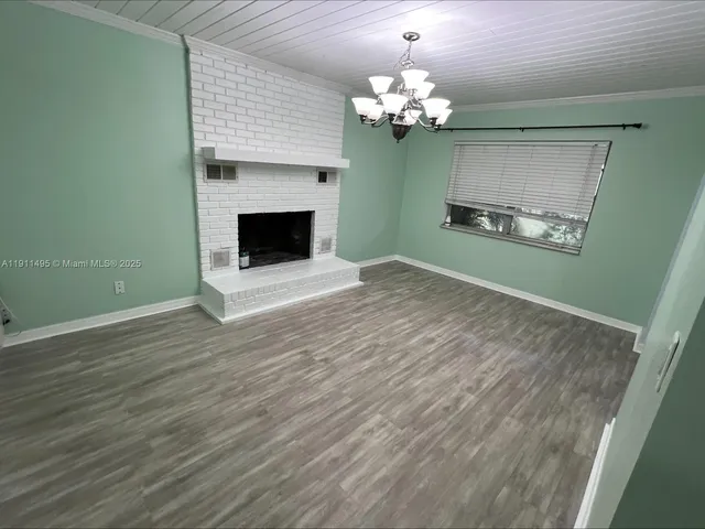 a view of a livingroom with a fireplace a chandelier and wooden floor