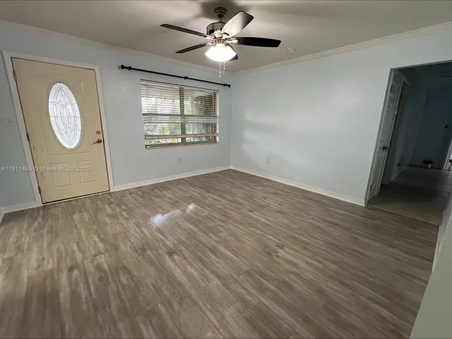 a view of an empty room with a window and wooden floor