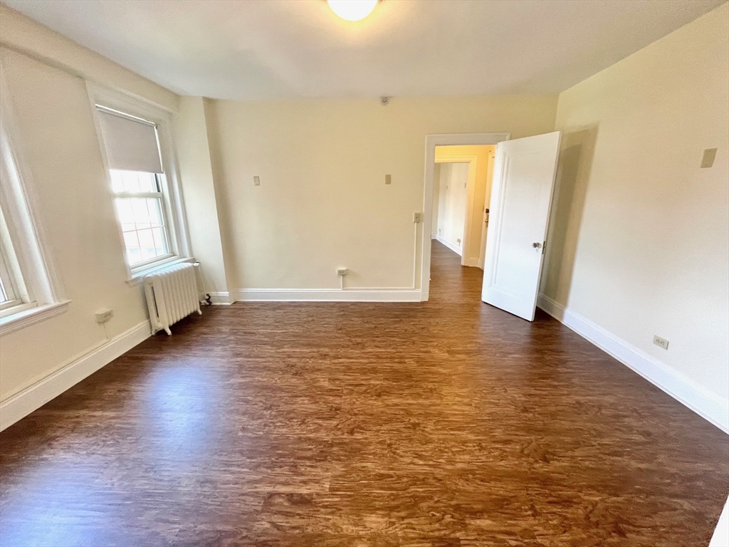 1401 Beacon Street, Unit 704 Brookline, MA 02446 - Photo 4 of 11 an empty room with wooden floor and windows
