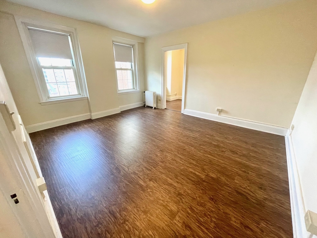 1401 Beacon Street, Unit 704 Brookline, MA 02446 - Photo 6 of 11 an empty room with wooden floor and windows
