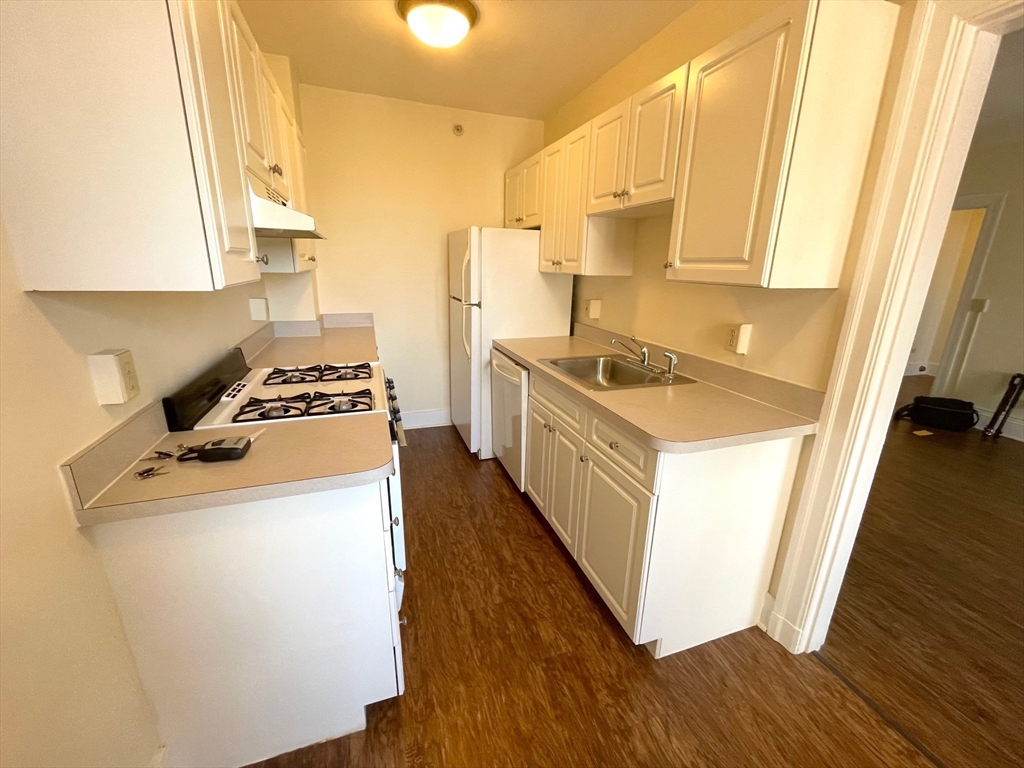 1401 Beacon Street, Unit 704 Brookline, MA 02446 - Photo 7 of 11 a kitchen with a stove a sink a refrigerator and wooden floor