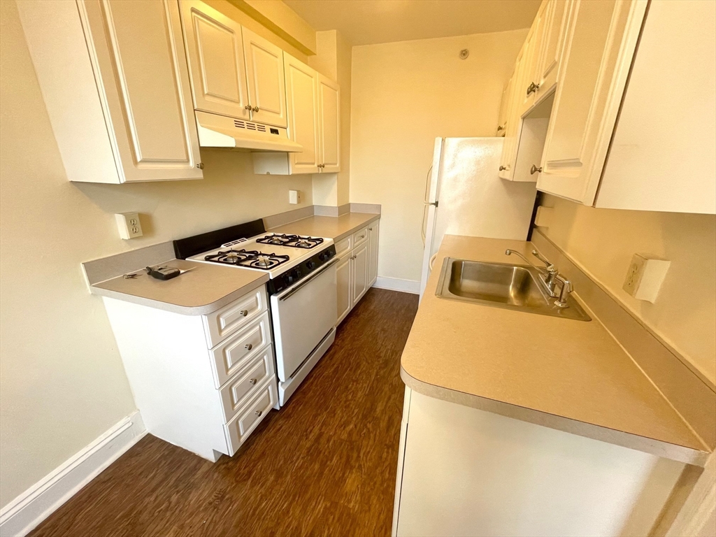 1401 Beacon Street, Unit 704 Brookline, MA 02446 - Photo 8 of 11 a kitchen with a stove a sink and a refrigerator