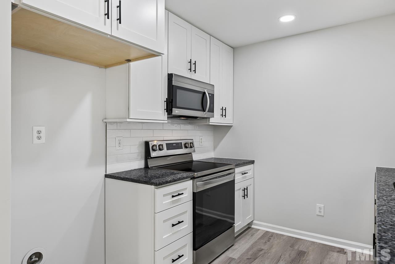 704 Hartford Road Raleigh, NC 27610 - Photo 12 of 29 a kitchen with granite countertop cabinets stainless steel appliances and wooden floor