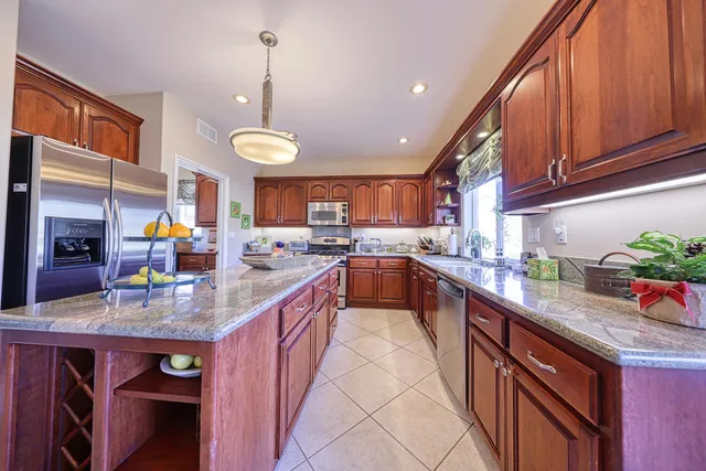 a kitchen with kitchen island granite countertop a stove a sink dishwasher and cabinets with wooden floor