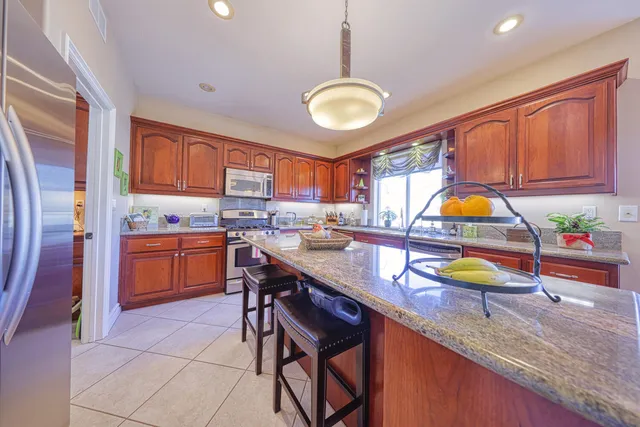 a kitchen with stainless steel appliances granite countertop a sink a stove and a wooden cabinets
