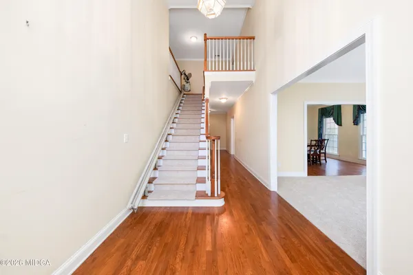a view of a hallway with wooden floor and stairs