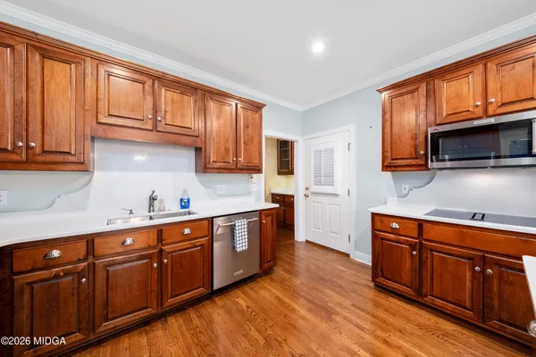 a kitchen with stainless steel appliances granite countertop wooden cabinets a sink and dishwasher a stove top oven with wooden floor