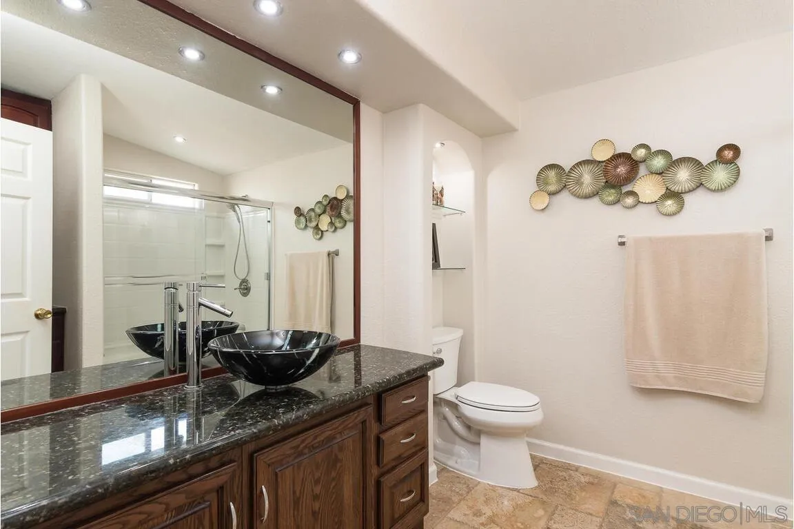 9399 Weber Court Spring Valley, CA 91977 - Photo 21 of 41 a bathroom with a granite countertop sink a toilet a mirror and shower
