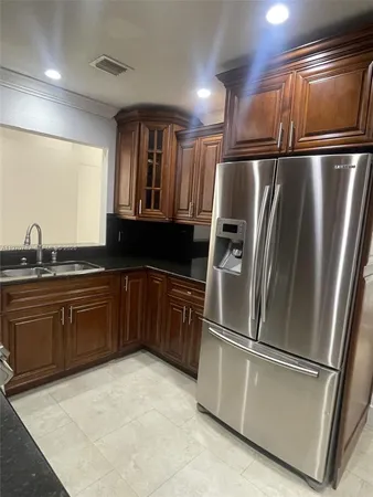 a kitchen with granite countertop stainless steel appliances a refrigerator a sink and cabinets