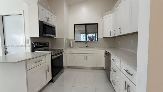 a kitchen with white cabinets appliances and a sink