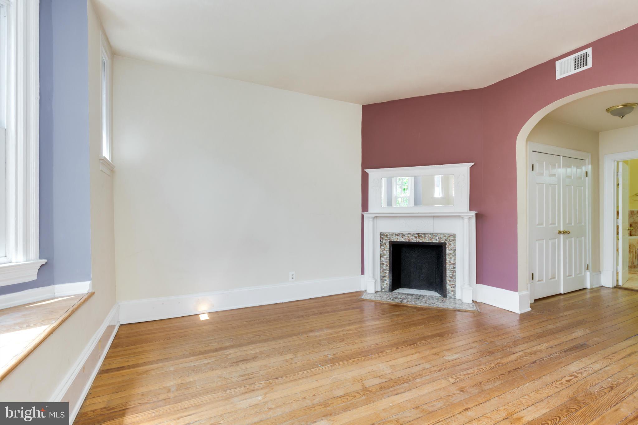1823 Kalorama Road Northwest Washington, DC 20009 - Photo 8 of 20 a view of an empty room with wooden floor fireplace and a window