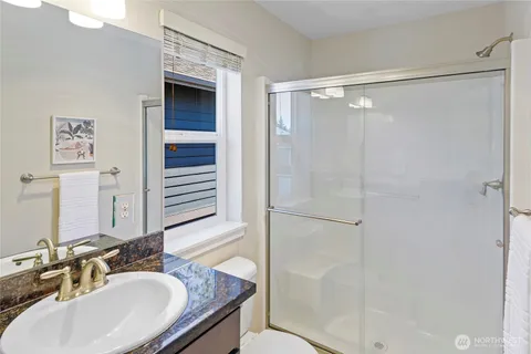a bathroom with a granite countertop shower sink and mirror