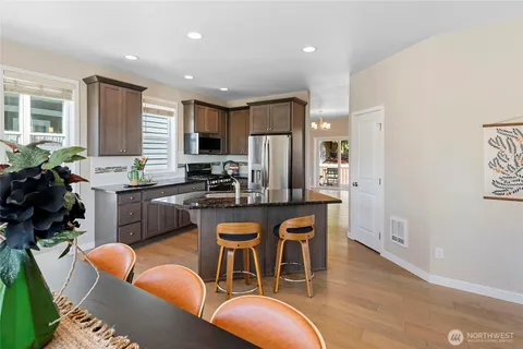a kitchen with stainless steel appliances granite countertop a dining table chairs refrigerator sink and cabinets