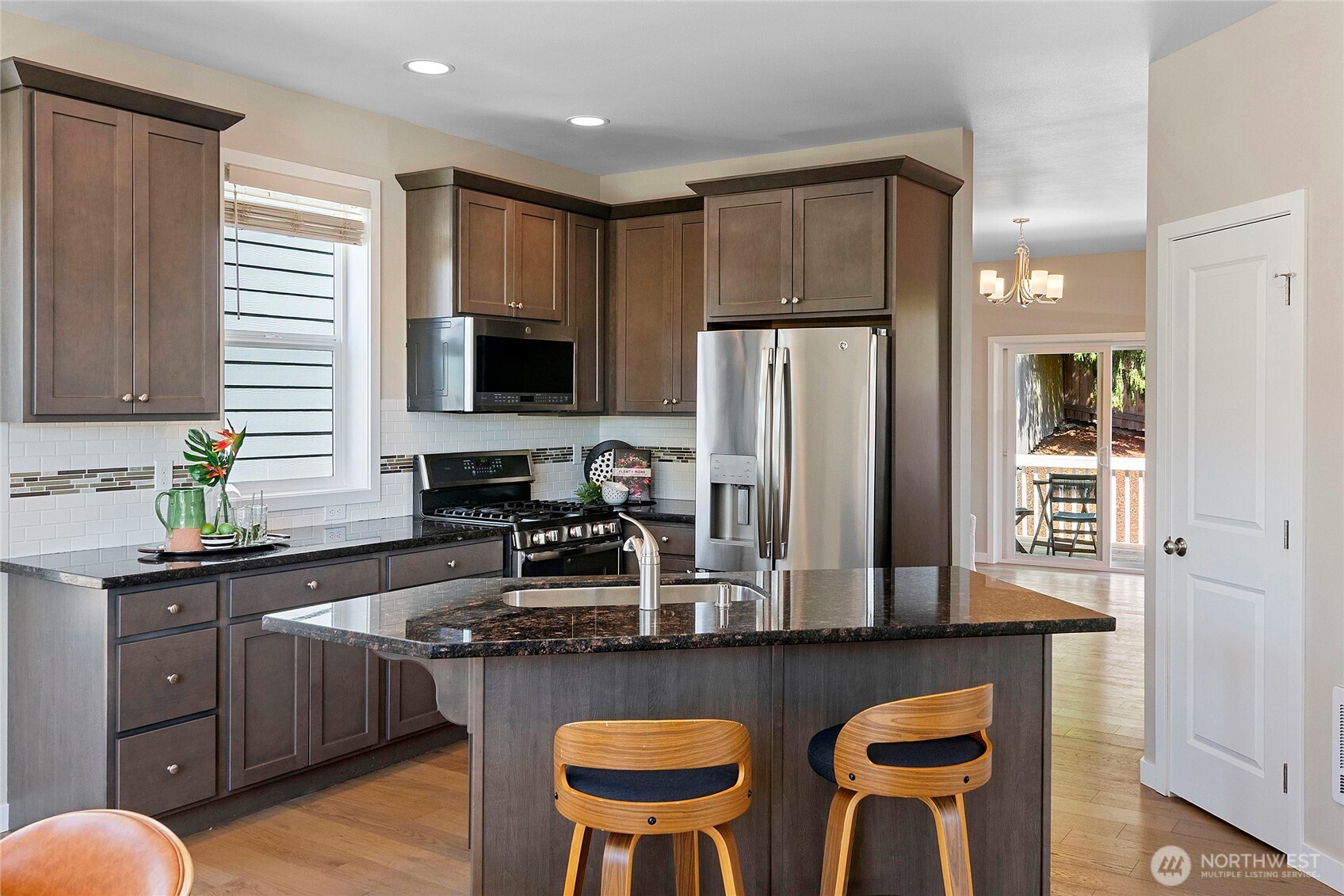 26442 GRAVITY Avenue Northeast Kingston, WA 98346 - Photo 10 of 40 a kitchen with stainless steel appliances granite countertop a stove a refrigerator a sink a dining table and chairs