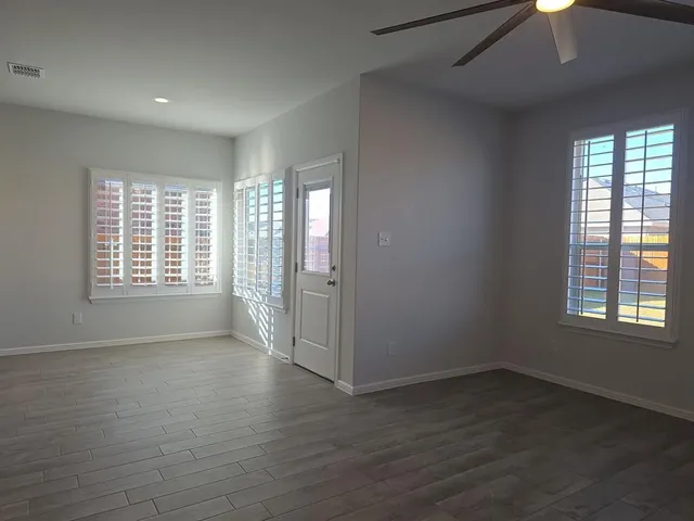 an empty room with wooden floor and windows