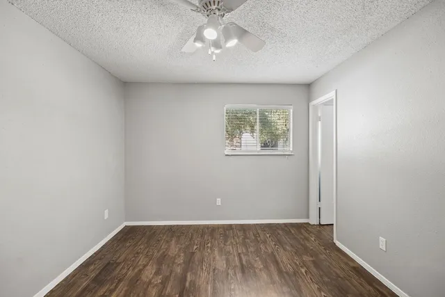 an empty room with wooden floor chandelier and fan
