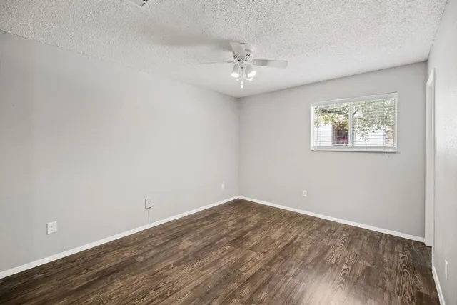an empty room with wooden floor and ceiling fan