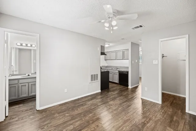 an empty room with wooden floor kitchen view and a window