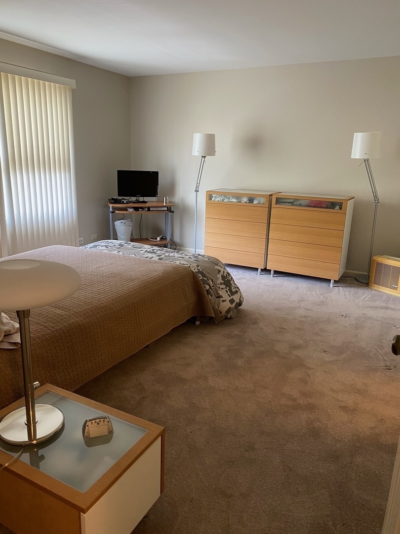 601 Ridge Road, Unit 402 Wilmette, IL 60091 - Photo 14 of 19 a bedroom with a bed and a lamp on table