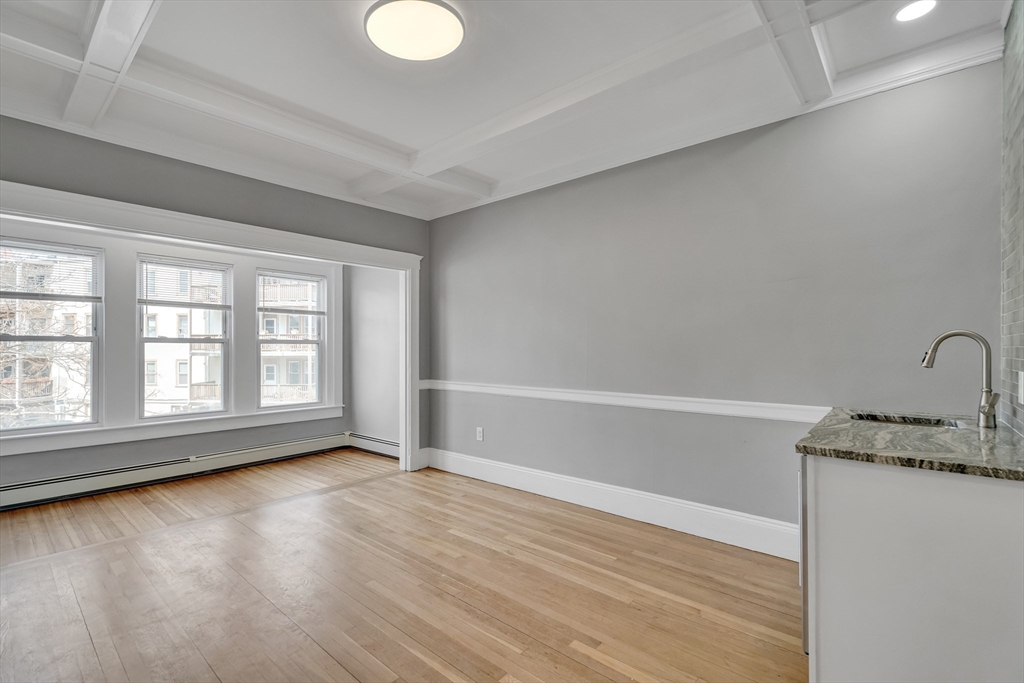 142 Sutherland Road, Unit 1 Boston, MA 02135 - Photo 2 of 16 an empty room with wooden floor and windows