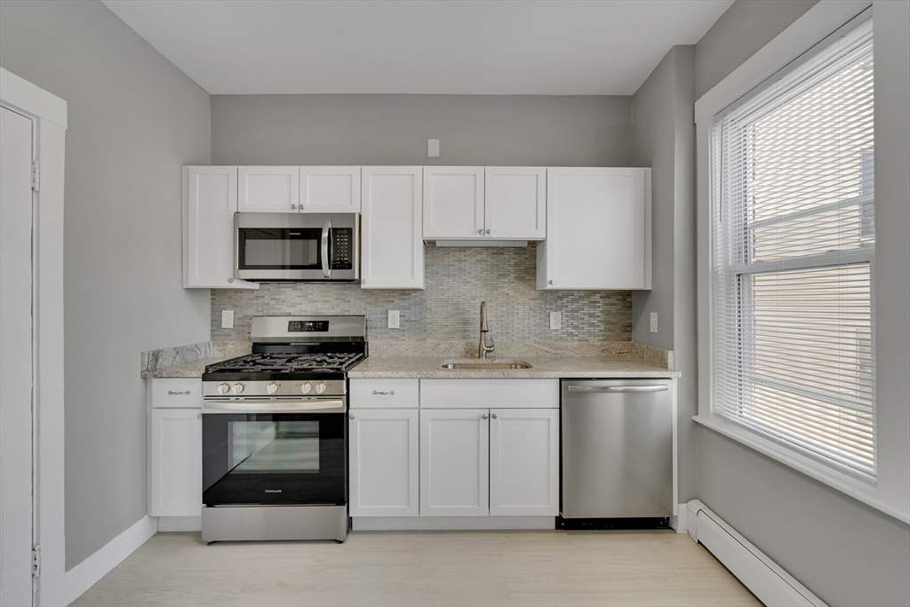 142 Sutherland Road, Unit 1 Boston, MA 02135 - Photo 4 of 16 a kitchen with cabinets appliances a sink and a window
