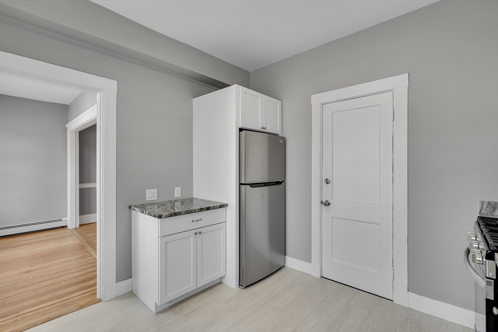142 Sutherland Road, Unit 1 Boston, MA 02135 - Photo 6 of 16 a kitchen with white cabinets and stainless steel appliances