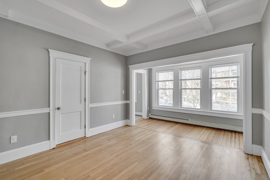142 Sutherland Road, Unit 1 Boston, MA 02135 - Photo 7 of 16 an empty room with wooden floor and windows