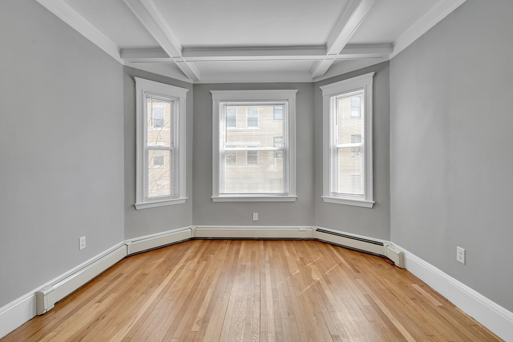 142 Sutherland Road, Unit 1 Boston, MA 02135 - Photo 9 of 16 an empty room with wooden floor and windows
