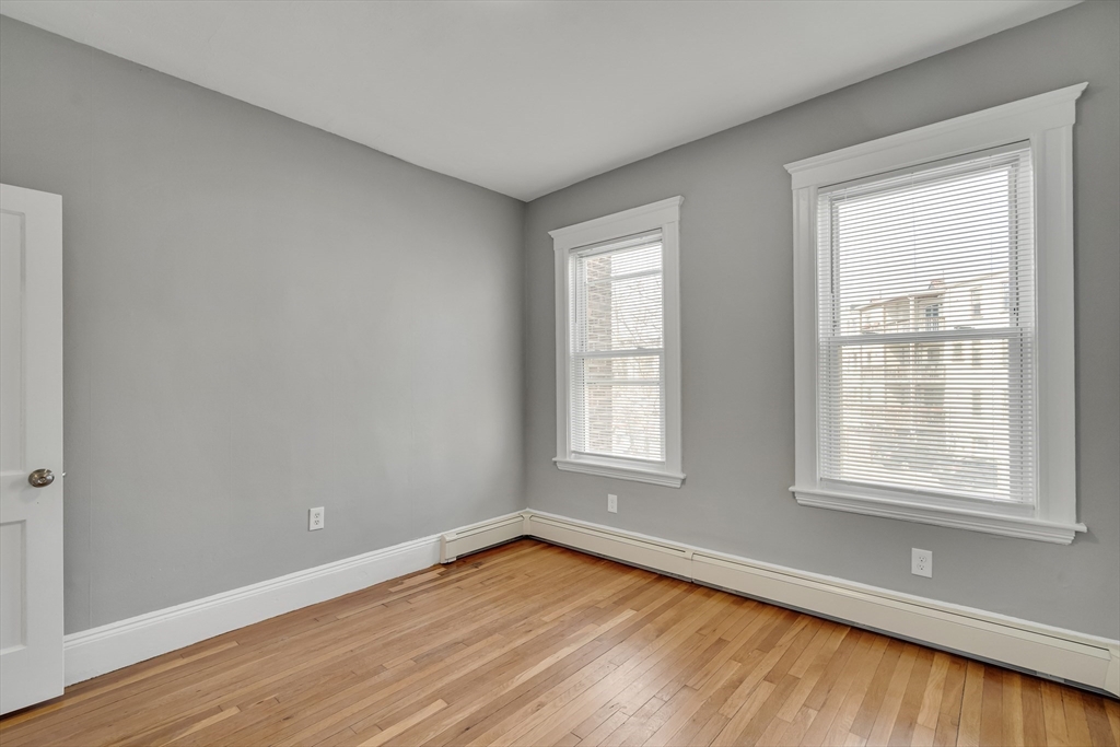 142 Sutherland Road, Unit 1 Boston, MA 02135 - Photo 10 of 16 an empty room with wooden floor and windows