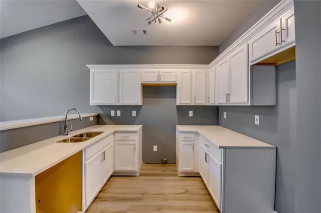 a kitchen with a sink dishwasher and white cabinets with wooden floor
