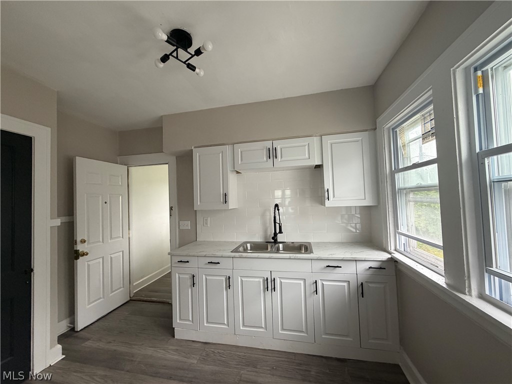 15317 Shiloh Road Cleveland, OH 44110 - Photo 16 of 29 Modern kitchen featuring white cabinetry, a dual basin stainless steel sink with a matte black faucet, and a white subway tile backsplash