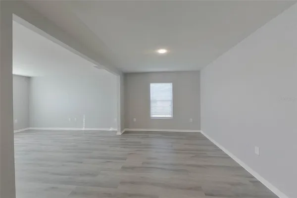 a view of an empty room with wooden floor and window