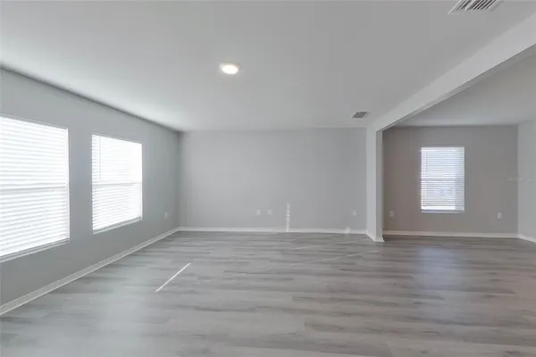 a view of an empty room with wooden floor and window