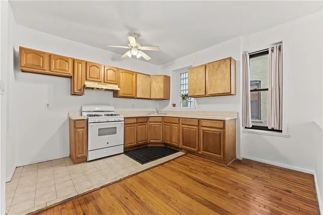 a kitchen with stainless steel appliances a white stove top oven cabinets and a wooden floor