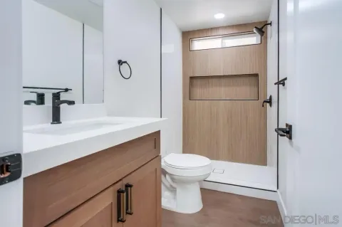 a bathroom with a sink a toilet a mirror and shower