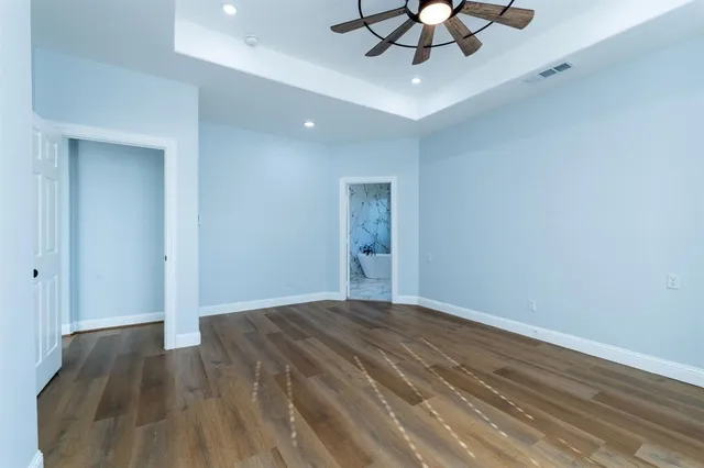 wooden floor in an empty room with a chandelier fan