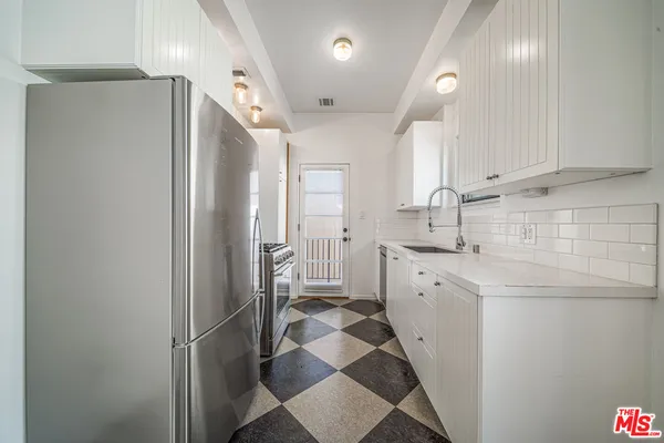a kitchen with stainless steel appliances a refrigerator sink and white cabinets
